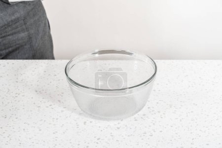 Foto de Levantamiento de la masa en un recipiente de mezcla de vidrio para hornear bañadores naan. - Imagen libre de derechos