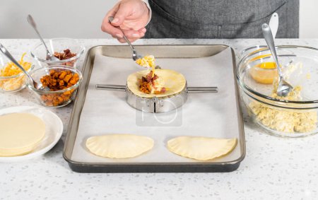 Photo for Filling empanada dough with egg filling to make breakfast empanadas with eggs and sweet potato. - Royalty Free Image