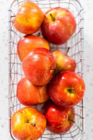 Téléchargez les photos : Pommes rouges dans un panier métallique sur le comptoir de la cuisine. - en image libre de droit