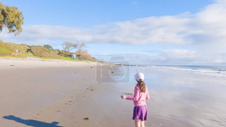 Photo for A little girl joyfully plays on the vast, empty sands of El Capitan State Beach in California during winter. - Royalty Free Image