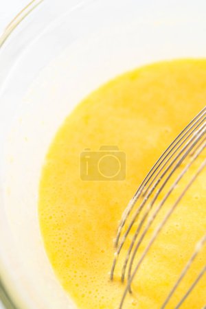 Photo for Mixing wet ingredients in a large glass mixing bowl to bake lemon blueberry bundt cake. - Royalty Free Image