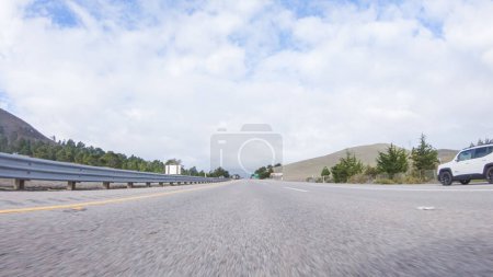 Photo for Santa Maria, California, USA-December 6, 2022-On a crisp winter day, a car cruises along the iconic Highway 101 near San Luis Obispo, California. The surrounding landscape is brownish and subdued - Royalty Free Image