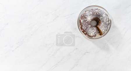Photo for Flat lay. Slicing gingerbread bundt cake with caramel filling, buttercream frosting, and powdered sugar dusting. - Royalty Free Image