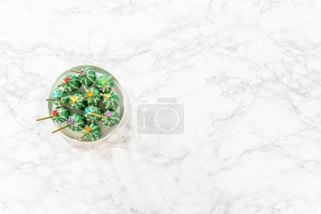 Photo for Flat lay. Cactus-shaped cake pops, beautifully decorated with luster dust, sugar flowers, and white sprinkles, arranged in celebration of Cinco de Mayo. - Royalty Free Image
