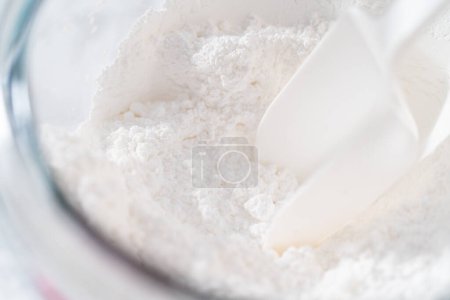 Photo for Mixing ingredients in a large glass mixing bowl to make homemade royal icing. - Royalty Free Image
