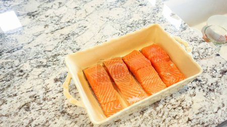 Téléchargez les photos : Dans une cuisine blanche moderne, le saumon cru est généreusement recouvert de sauce teriyaki. - en image libre de droit