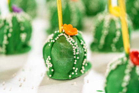 Photo for Cactus-shaped cake pops, beautifully decorated with luster dust, sugar flowers, and white sprinkles, arranged in celebration of Cinco de Mayo. - Royalty Free Image