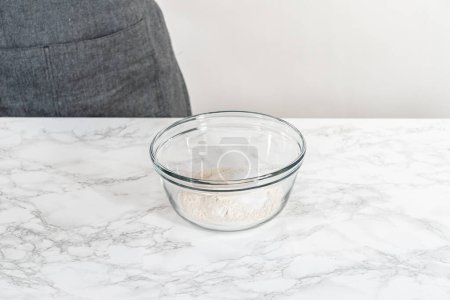 Téléchargez les photos : Mélanger les ingrédients secs avec un fouet à la main dans un bol de mélange en verre pour cuire des muffins de graines de pavot citron. - en image libre de droit