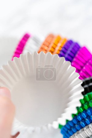 Foto de Nuevos revestimientos de cupcakes de papel de aluminio de diferentes colores en el mostrador de la cocina. - Imagen libre de derechos