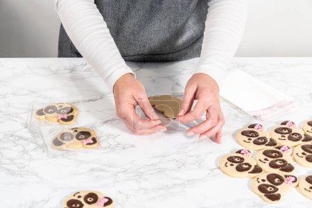 Photo for Packaging panda-shaped shortbread cookies with chocolate icing into individual clear bags. - Royalty Free Image