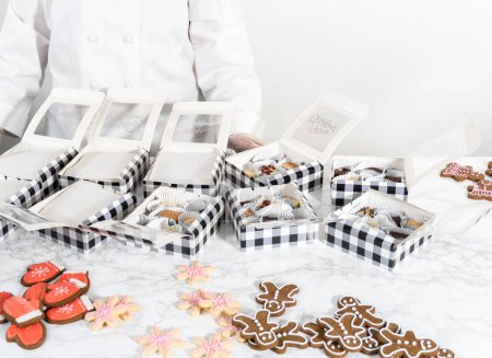 Foto de Embalaje de una variedad casera de galletas de caramelo y pan de jengibre para regalos de comida navideña en cajas de papel. - Imagen libre de derechos