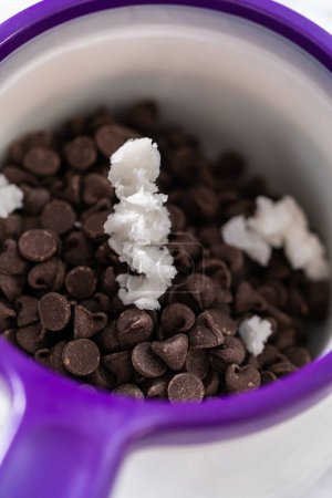 Foto de Derretir chispas de chocolate en un crisol de dulces para hacer glaseado de chocolate para galletas de shortbread en forma de panda. - Imagen libre de derechos