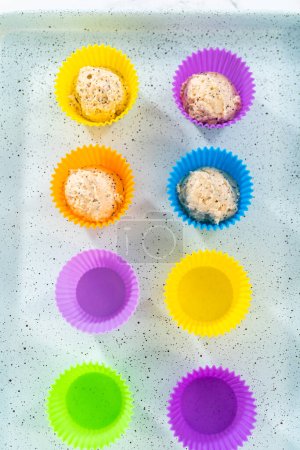 Foto de Recoger la masa de magdalenas con cuchara de masa en revestimientos de magdalenas de silicio para muffins de semillas de amapola de limón. - Imagen libre de derechos