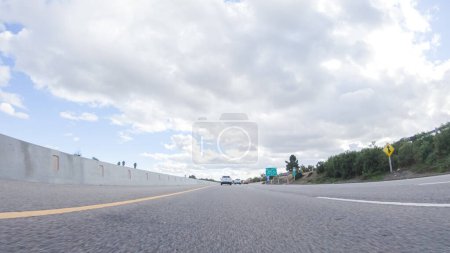 Téléchargez les photos : Par une journée nuageuse d'hiver, une voiture se déplace en douceur le long de l'autoroute 101 près de Santa Maria, Californie, sous un ciel nuageux, entouré d'un mélange de verdure et de nuances dorées. - en image libre de droit