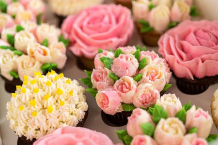 Téléchargez les photos : Enveloppé dans une boîte à cupcake en papier blanc immaculé, chaque cupcake gourmet est une œuvre d'art, ornée de fleurs de glaçage à la crème au beurre magnifiquement conçues pour ressembler à des roses et des tulipes vibrantes.. - en image libre de droit
