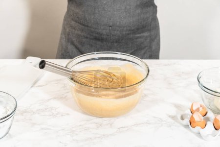 Foto de En un tazón de vidrio grande, los ingredientes se mezclan expertamente para crear la masa para hornear el delicioso pastel de zanahoria Bundt. - Imagen libre de derechos