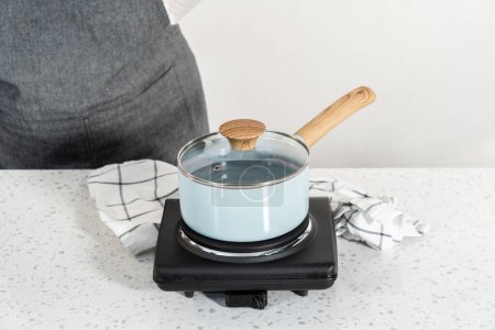 Foto de Boiling water in a cooking pot to prepare chocolate pistachio fudge. - Imagen libre de derechos