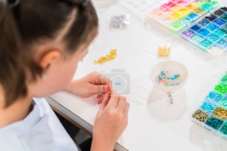 Foto de Niña disfruta de la elaboración de pulseras de colores con vibrantes cuentas de arcilla conjunto. - Imagen libre de derechos
