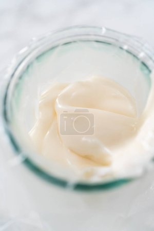 Photo for Transferring homemade royal icing into the piping bags for decorating sugar cookies. - Royalty Free Image