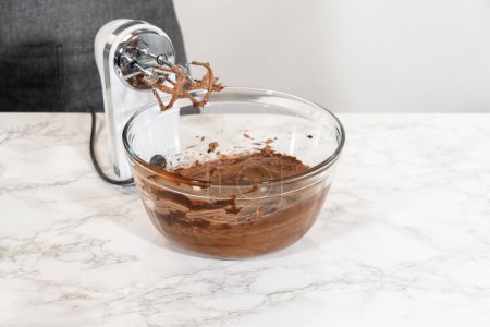 Téléchargez les photos : Le glaçage est fouetté à la perfection avant d'être canalisé sur les délicieux cupcakes au chocolat. - en image libre de droit