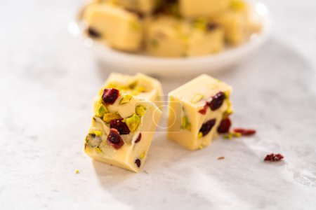 Téléchargez les photos : Pièces carrées de caramel à la pistache aux canneberges fait maison sur un comptoir de cuisine. - en image libre de droit