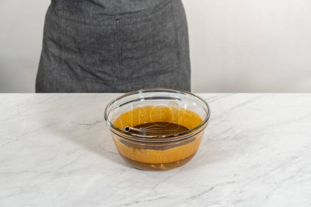Téléchargez les photos : Mélanger les ingrédients humides dans un petit bol à mélanger en verre pour cuire le gâteau bundt au pain d'épice avec le remplissage au caramel - en image libre de droit