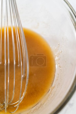 Photo for Mixing wet ingredients in a small glass mixing bowl to bake gingerbread bundt cake with caramel filling - Royalty Free Image