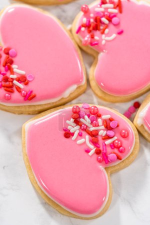 Decoración de galletas de azúcar en forma de corazón con glaseado real rosa y blanco para el Día de San Valentín.