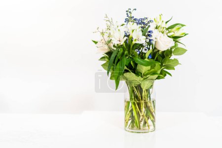 Téléchargez les photos : Un magnifique bouquet de roses blanches fraîches et de fleurs assorties disposées gracieusement dans un vase, exsudant une beauté intemporelle. - en image libre de droit