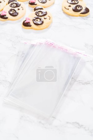 Foto de Embalaje galletas de shortbread en forma de panda con glaseado de chocolate en bolsas claras individuales. - Imagen libre de derechos