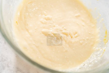 Téléchargez les photos : Mélanger les ingrédients avec un mélangeur à main dans un grand bol à mélanger pour faire la garniture de fromage à la crème pour gâteau bundt aux carottes. - en image libre de droit