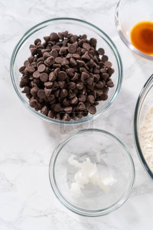 Foto de Ingredientes medidos en tazones de vidrio para hornear galletas de shortbread en forma de panda con glaseado de chocolate. - Imagen libre de derechos