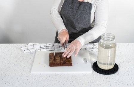 Photo for Cutting chocolate peanut butter fudge into small pieces on a white cutting board. - Royalty Free Image