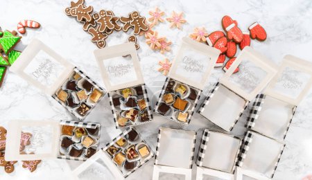 Foto de Acostado. Embalaje de una variedad casera de galletas de caramelo y pan de jengibre para regalos de comida navideña en cajas de papel. - Imagen libre de derechos