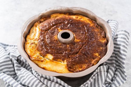 Téléchargez les photos : Enlever le gâteau bundt aux carottes fraîchement cuit du moule à gâteau bundt pour arrondir le rack de refroidissement. - en image libre de droit