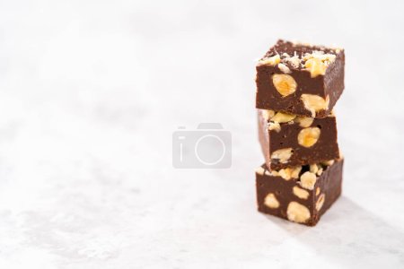 Photo for Homemade chocolate hazelnut fudge square pieces stacked on the kitchen counter. - Royalty Free Image