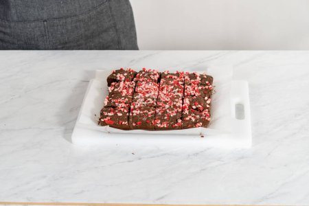 Photo for Cutting freshly baked peppermint brownies with chocolate peppermint chips into squares. - Royalty Free Image
