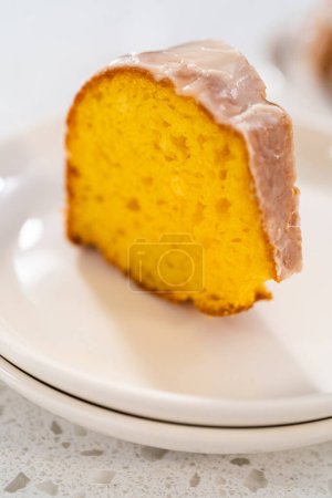 Photo for Sliced vanilla bundt cake with a white glaze on a white plate. - Royalty Free Image