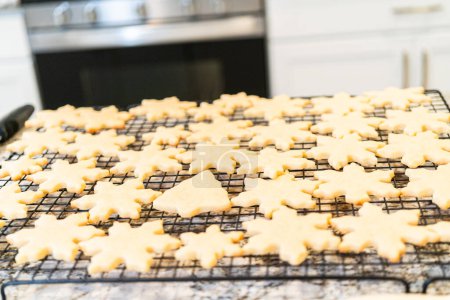 Téléchargez les photos : Laisser refroidir les délicieux biscuits au sucre en forme de flocon de neige sur un support, les préparant pour des cadeaux de Noël festifs. - en image libre de droit