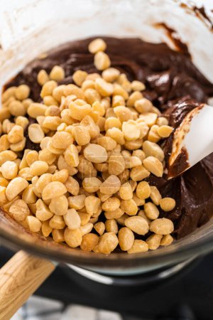 Téléchargez les photos : Faire fondre les pépites de chocolat blanc et d'autres ingrédients dans un bol de mélange en verre sur de l'eau bouillante pour préparer le fudge macadamia au chocolat. - en image libre de droit