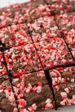 Téléchargez les photos : Découper des brownies à la menthe poivrée fraîchement cuits avec des pépites de menthe poivrée au chocolat en carrés. - en image libre de droit
