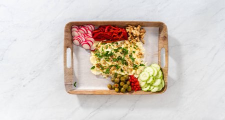 Photo for Flat lay. Arranging fresh and pickled vegetables on a serving tray to prepare a vegetarian party butter board for a party. - Royalty Free Image