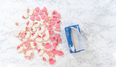 Photo for Denver, Colorado, USA-February 9, 2023-Flat lay. Storing heart-shaped sugar cookies with pink and white royal icing in a large plastic container. - Royalty Free Image