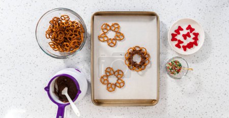 Foto de Flat lay. Dipping pretzels twists into melted chocolate to make a chocolate pretzel Christmas wreath. - Imagen libre de derechos