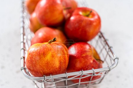 Foto de Manzanas rojas en una canasta de alambre en el mostrador de la cocina. - Imagen libre de derechos