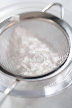 Foto de Polvo de polvo de azúcar para la torta de paquete en un tamiz pequeño. - Imagen libre de derechos