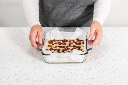 Photo for Removing white chocolate cranberry pecan fudge from the baking pan lined with parchment. - Royalty Free Image