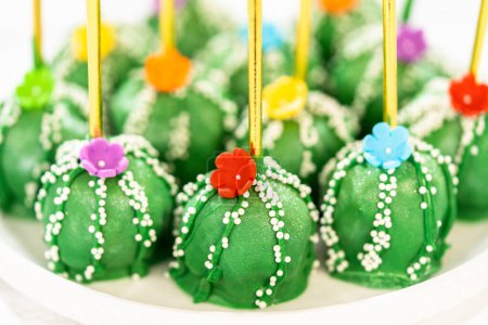 Photo for Cactus-shaped cake pops, beautifully decorated with luster dust, sugar flowers, and white sprinkles, arranged in celebration of Cinco de Mayo. - Royalty Free Image