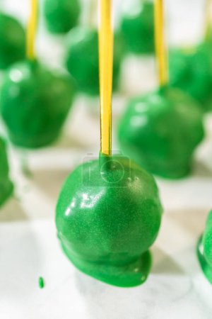 Photo for Dipping dough balls into green melted chocolate to make cactus cake pops for the Cinco de Mayo celebration. - Royalty Free Image