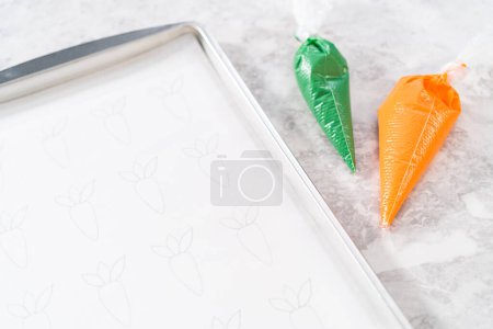 Téléchargez les photos : Piping chocolat fondu à partir d'un sac de tuyauterie sur le papier parchemin pour faire des garnitures de gâteau aux carottes au chocolat. - en image libre de droit